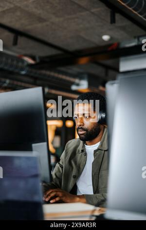 Serious male computer programmer working on computer at desk in office Stock Photo