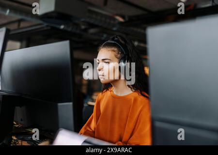 Focused female computer programmer with wireless headphones working at office Stock Photo