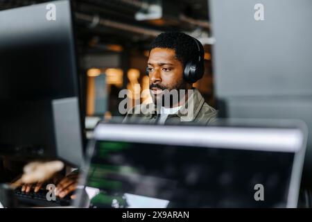 Focused male programmer working with wireless headphones at office Stock Photo