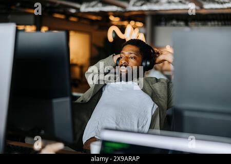 Tired male computer programmer stretching while working at tech start up office Stock Photo