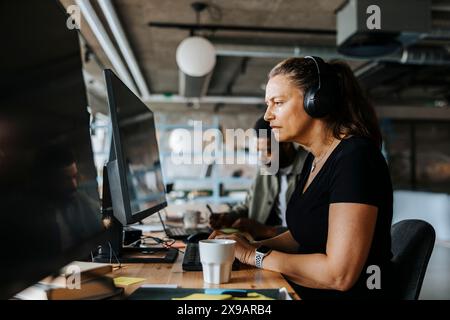 Focused female programmer coding while sitting at desk in tech start up office Stock Photo