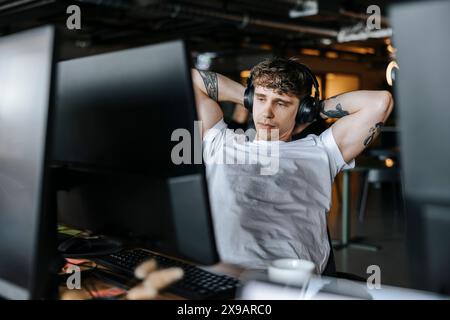 Tired male entrepreneur stretching arms while sitting at desk in office Stock Photo