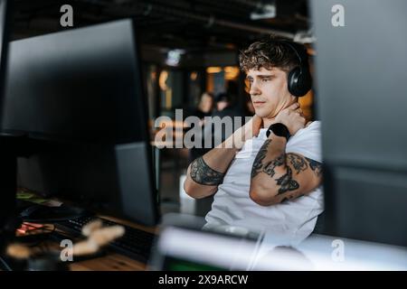 Young male entrepreneur with tattooed arms taking break while sitting at office Stock Photo