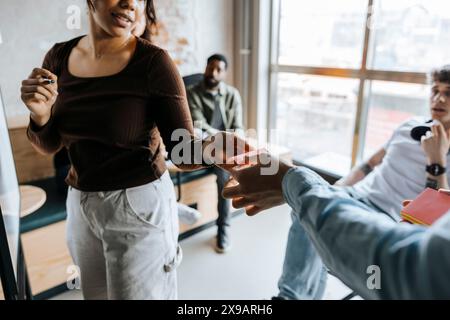 Female entrepreneur passing adhesive note of colleague in meeting at office Stock Photo