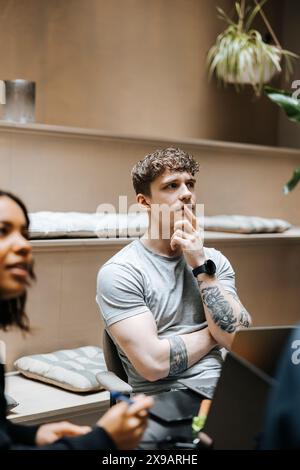 Thoughtful young male entrepreneur with hand on chin in meeting at office Stock Photo