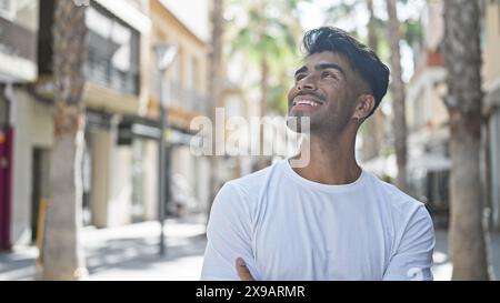Handsome young man smiling outdoors in an urban street setting, exuding confidence and casual style. Stock Photo