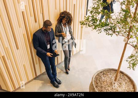 High angle view of businessman using digital tablet while standing next to female entrepreneur near wall at convention c Stock Photo