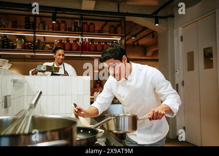 Male chef preparing food with spatula in commercial kitchen Stock Photo