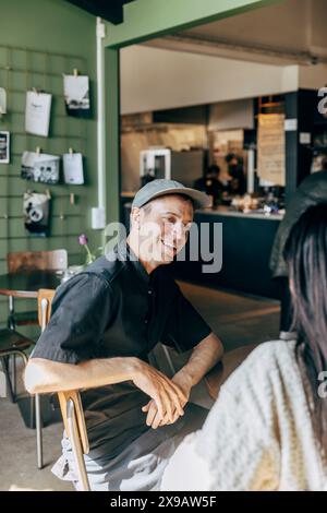 Happy male owner talking with female coworker while sitting at cafe Stock Photo
