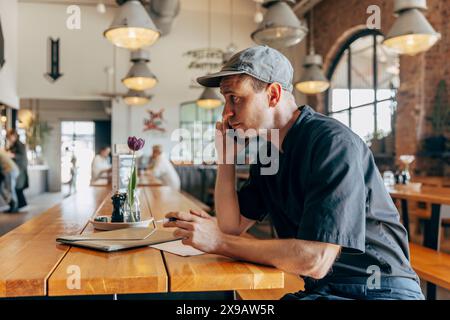 Male owner talking on smart phone while sitting in coffee shop Stock Photo