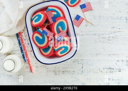 4th of July Holiday background. Red white and blue pinwheel sugar cookies with milk glass for July 4th celebration on old white wooden background. Pat Stock Photo