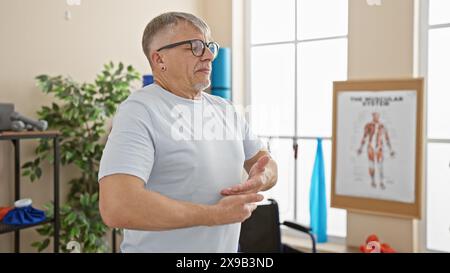 A mature grey-haired man exercises indoors at a rehabilitation clinic Stock Photo