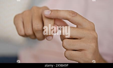 Close-up of a young man's hands using sign language indoor, with a blurred background. Stock Photo