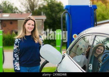Woman inserts plug into the electric car charging socket Stock Photo