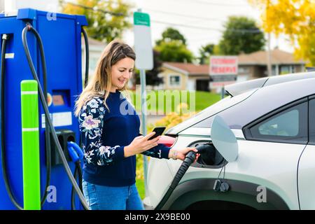 Woman inserts plug into the electric car charging socket Stock Photo