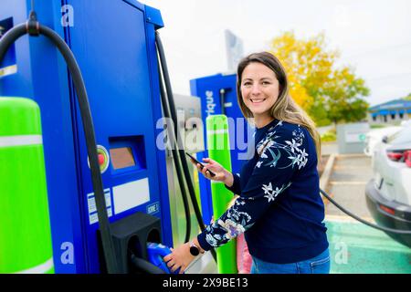 Woman inserts plug into the electric car charging socket Stock Photo