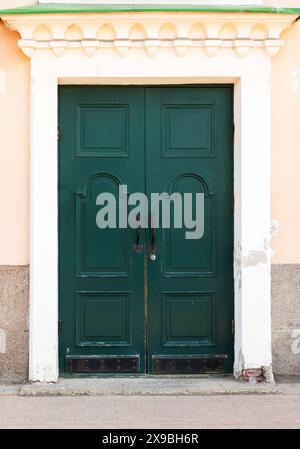 Vintage green wooden door in yellow stone wall. Vyborg old town Stock Photo