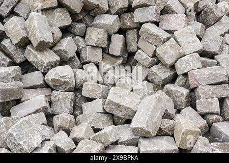 Pile of historic hammered cube shape natural granite cobblestones, background of hammered granite rocks, granite stones, paving stones Stock Photo