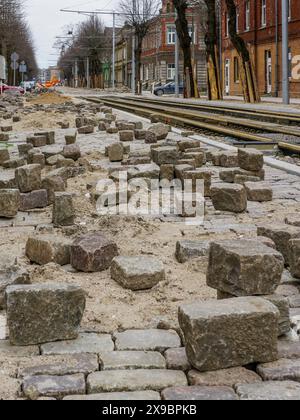 Close-up of historic cube-shaped hammered and chiseled natural granite paving stones on an unfinished street pavement Stock Photo