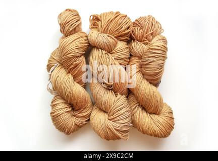 Table top photo of three twisted beige yarn hanks isolated on a white background, flat lay of hand dyed wool skeins Stock Photo