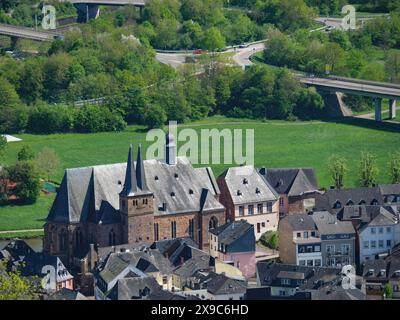 A historic church in a village surrounded by green spaces and rural architecture in a spring landscape, small town on a river between green hills Stock Photo