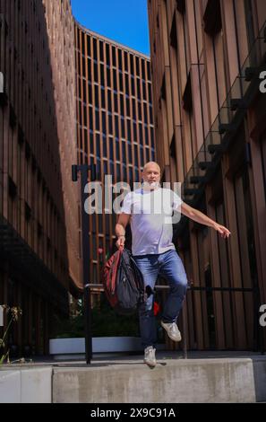 Old businessman middle-aged Caucasian employee senior business man worker dancing walking down stairs office in city happy good mood success jump Stock Photo