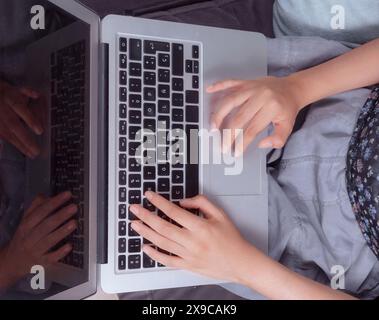 Close-up of hands typing on a laptop keyboard, woman doing homework at home. Stock Photo