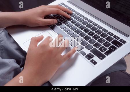 Close-up of hands typing on a laptop keyboard, woman doing homework at home. Stock Photo