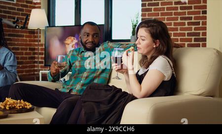 Company employees celebrating business success at work, gathered at home to toast wine drinks for their accomplishments, throwing house party in stylish living room Stock Photo