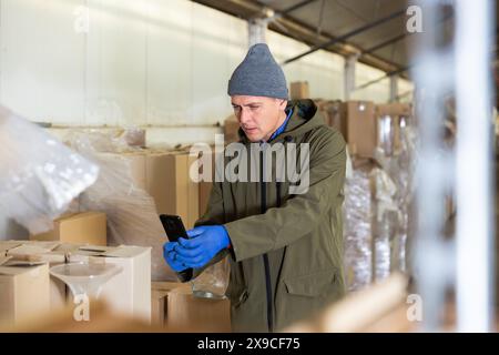 Warehouse worker using his smartphone to take photographs Stock Photo