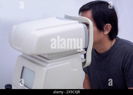 Young handsome asian man take eye exam with optical eye test machine Stock Photo