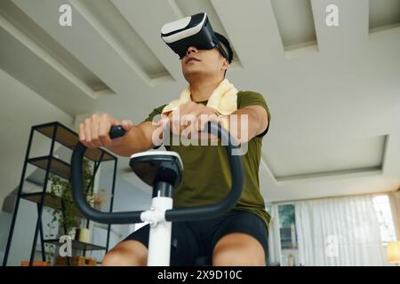 A man using a VR headset while exercising on a stationary bike in a modern living space with a relaxed atmosphere Stock Photo