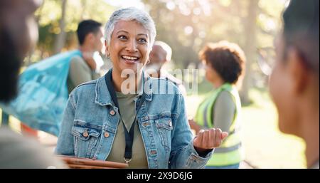 Park, woman and volunteers discussion with tablet for support, community project or nature sustainability. Humanitarian, recycling or senior leader in Stock Photo