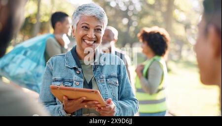 Park, woman and smile planning with tablet for volunteers, community project or nature sustainability. Humanitarian, recycling or senior leader in Stock Photo