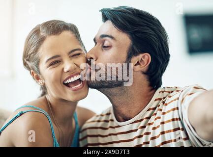 Couple, selfie and kiss in home with smile, care and love for post on social media with connection. Indian man, woman and happy with photography for Stock Photo