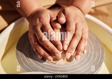 Close up of female hands carefully shaping clay on pottery wheel and making ceramics in sunlight copy space Stock Photo