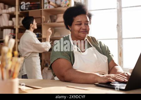 Portrait of African American senior woman using computer in art studio and managing small business copy space Stock Photo