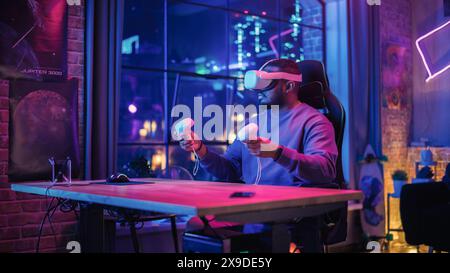 Stylish Man Using Virtual Reality Headset with Controllers at Home in Loft Apartment. Young African American Male Browsing Online, Spending Time in VR Digital Office. POV from Screen Perspective. Stock Photo