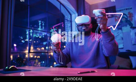 Young Man Using Virtual Reality Device with Controllers at Home in Loft Apartment. Stylish Black Male Browsing Online, Enjoying Time in VR Software and Digital Office. POV from Screen Perspective. Stock Photo