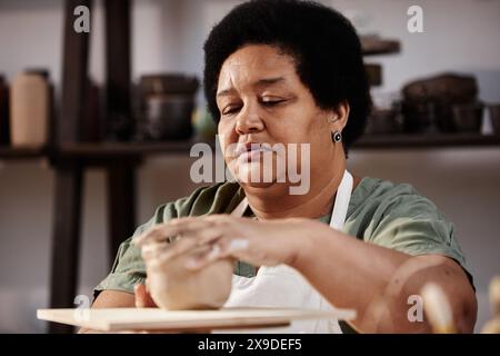 Portrait of senior woman enjoying creative hobby in retirement and shaping clay in pottery studio copy space Stock Photo