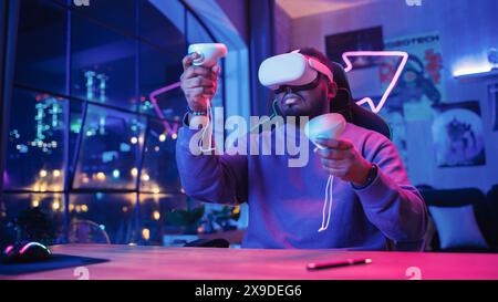Young Man Using Virtual Reality Device with Controllers at Home in Loft Apartment. Stylish Black Male Browsing Online, Spending Time in VR Software and Digital Office. POV from Screen Perspective. Stock Photo