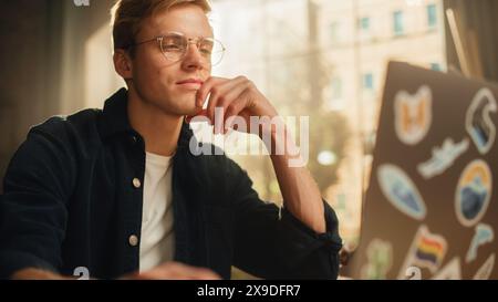 Focused Male Software Engineer Codding on Laptop Computer and Working With Inspiration in Modern Loft Flat. Man Creating New Mobile Application. Freelancer Doing Remote Work Concept. Stock Photo