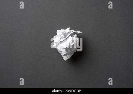 White paper crumpled into a ball on a dark gray background Stock Photo