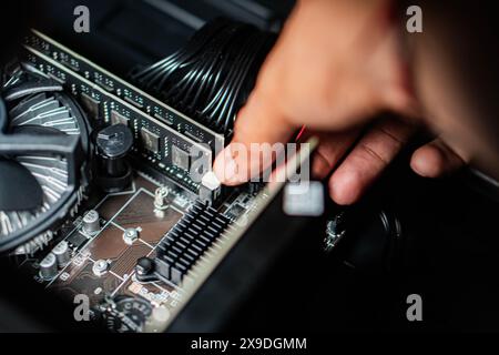 Close-up of a person installing or adjusting a component on a computer motherboard. The image shows a hand touching a connector on the motherboard, wi Stock Photo