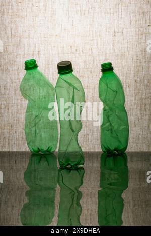 Three crumpled plastic bottles on a reflective surface Stock Photo