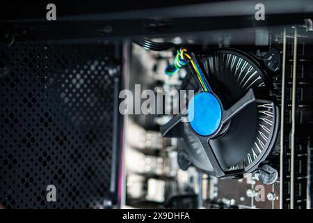 Close-up view of a computer CPU cooler with a blue fan inside a desktop case. The image shows the internal components of a computer, including the mot Stock Photo