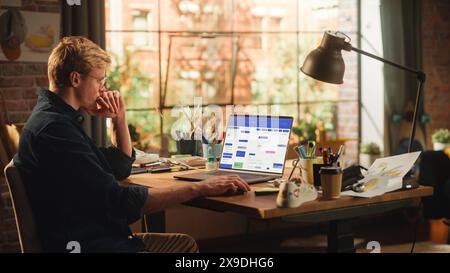 Young Handsome Man Works on Laptop Computer with Office Software on Display. Male Project Manager Checking Meetings in Calendar and Working Remotely. Home Office or Freelance Concept. Stock Photo