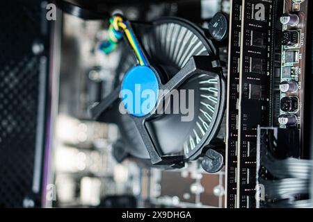 Close-up view of a computer CPU cooler with a fan inside a desktop PC. The image shows the cooling system and part of the motherboard. Stock Photo