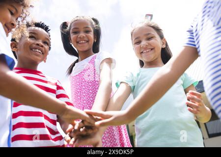 In school, diverse students are joining hands together outside Stock Photo