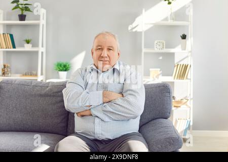 Serious Senior Man Sitting on Sofa at Home Stock Photo